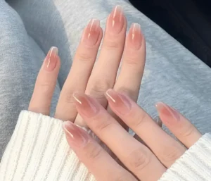 Hands with nude-colored jelly nails showcasing a translucent, natural look with a glossy finish.