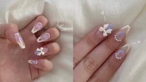 Korean gel nails with bow accents, pearl embellishments, and pastel hearts over a clear jelly base.